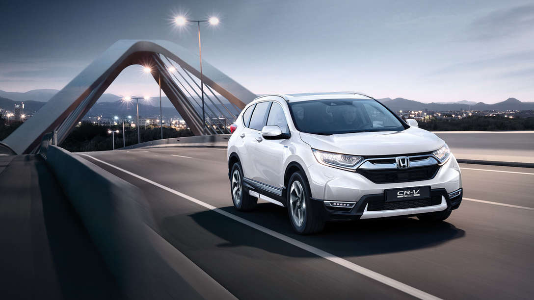 Trojštvrťový pohľad spredu na vozidlo Honda CR-V Hybrid idúce po ulici.