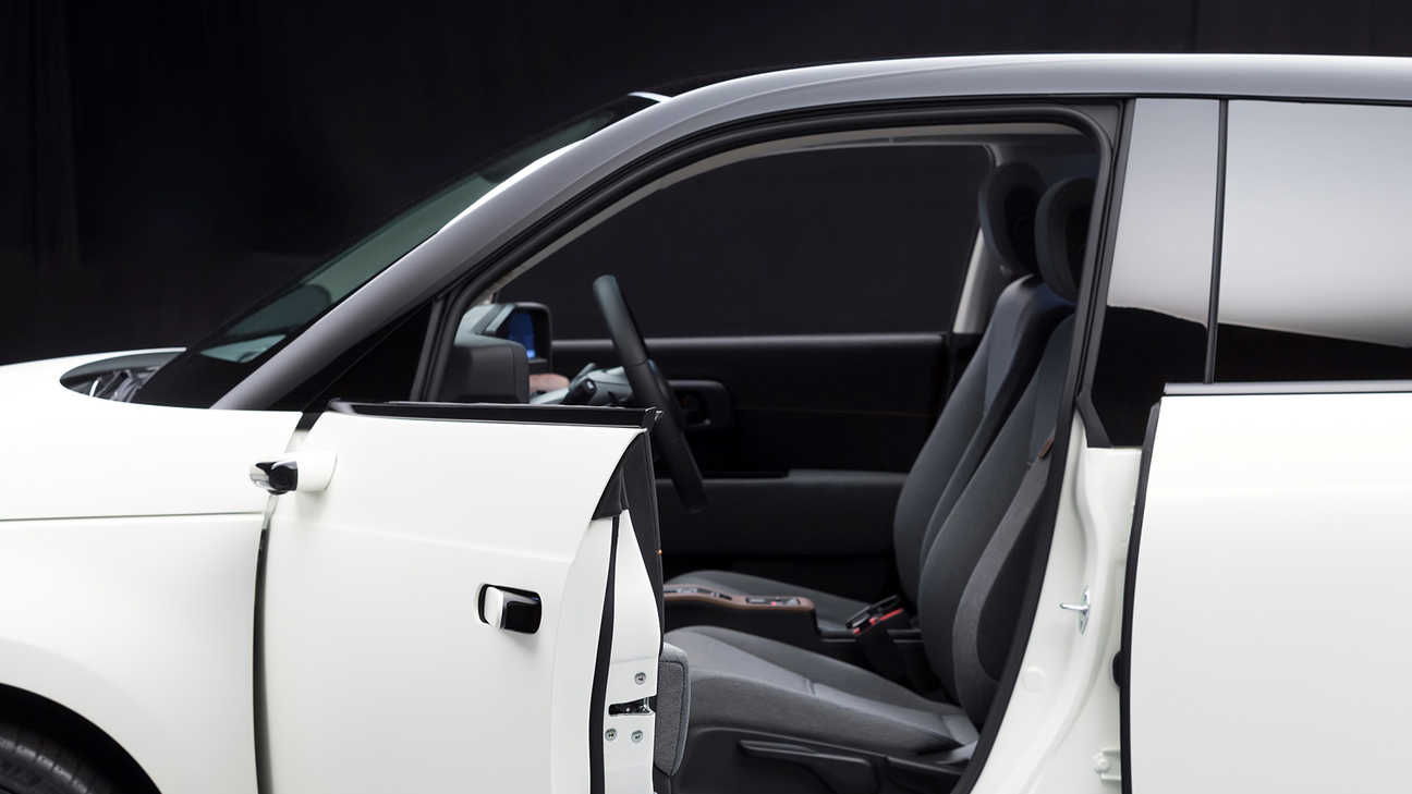 Side facing Honda e with open front door.