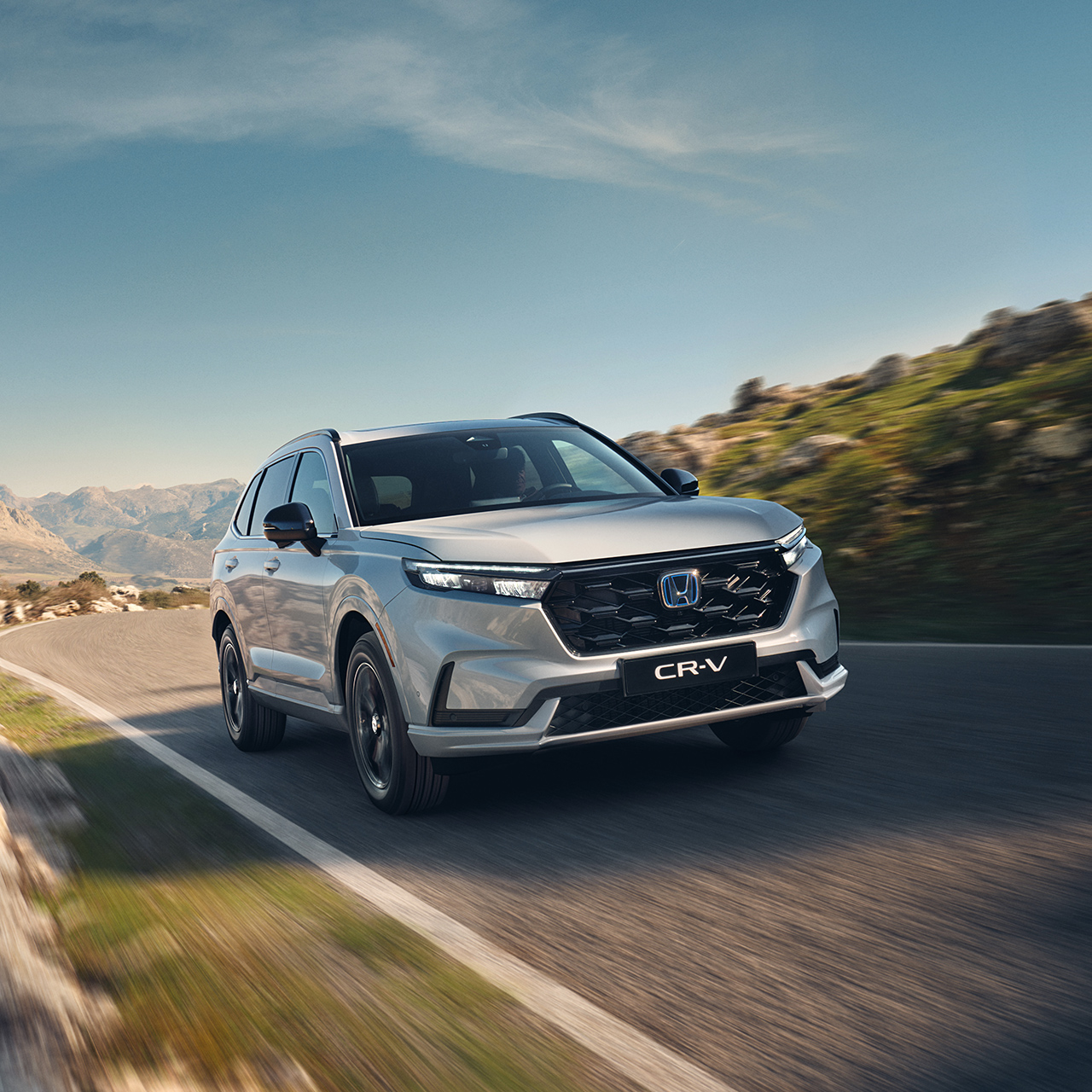 Biely plug-in hybrid CR-V pri jazde po ceste v horách.