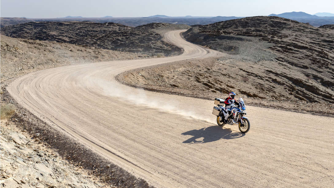 Honda Africa Twin Adventure Sports, trojštvrťový záber spredu z pravej strany, jazda po prašnej ceste v púšti