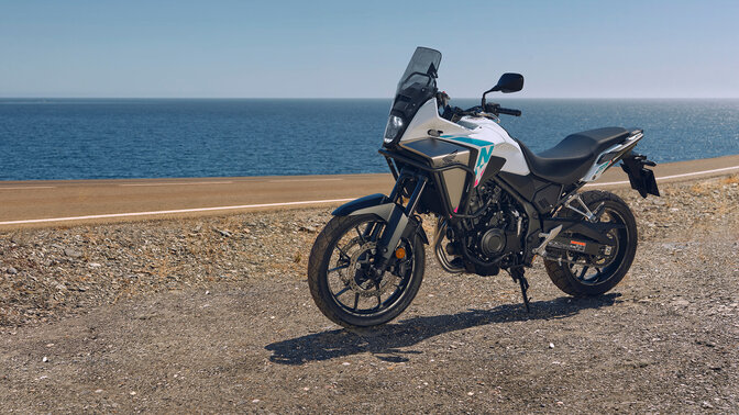 Bočný záber na model Honda NX500 v teréne pri pobreží