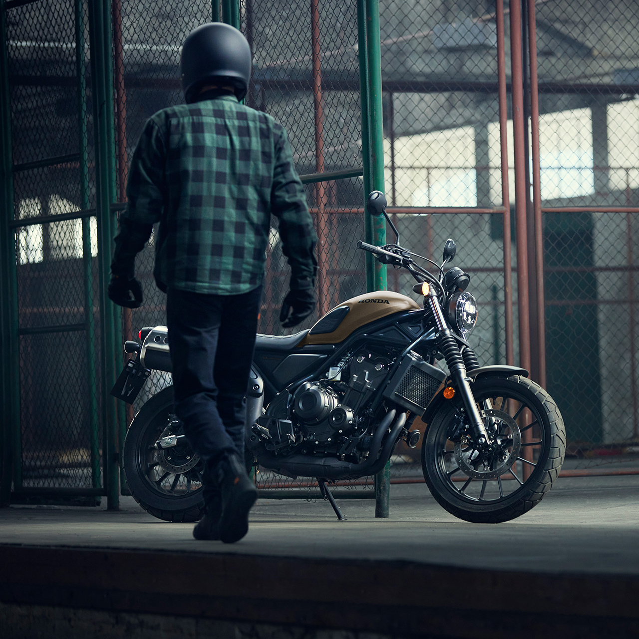 Jazdec kráčajúci vedľa zaparkovaného motocykla Honda CL500 v sklade.
