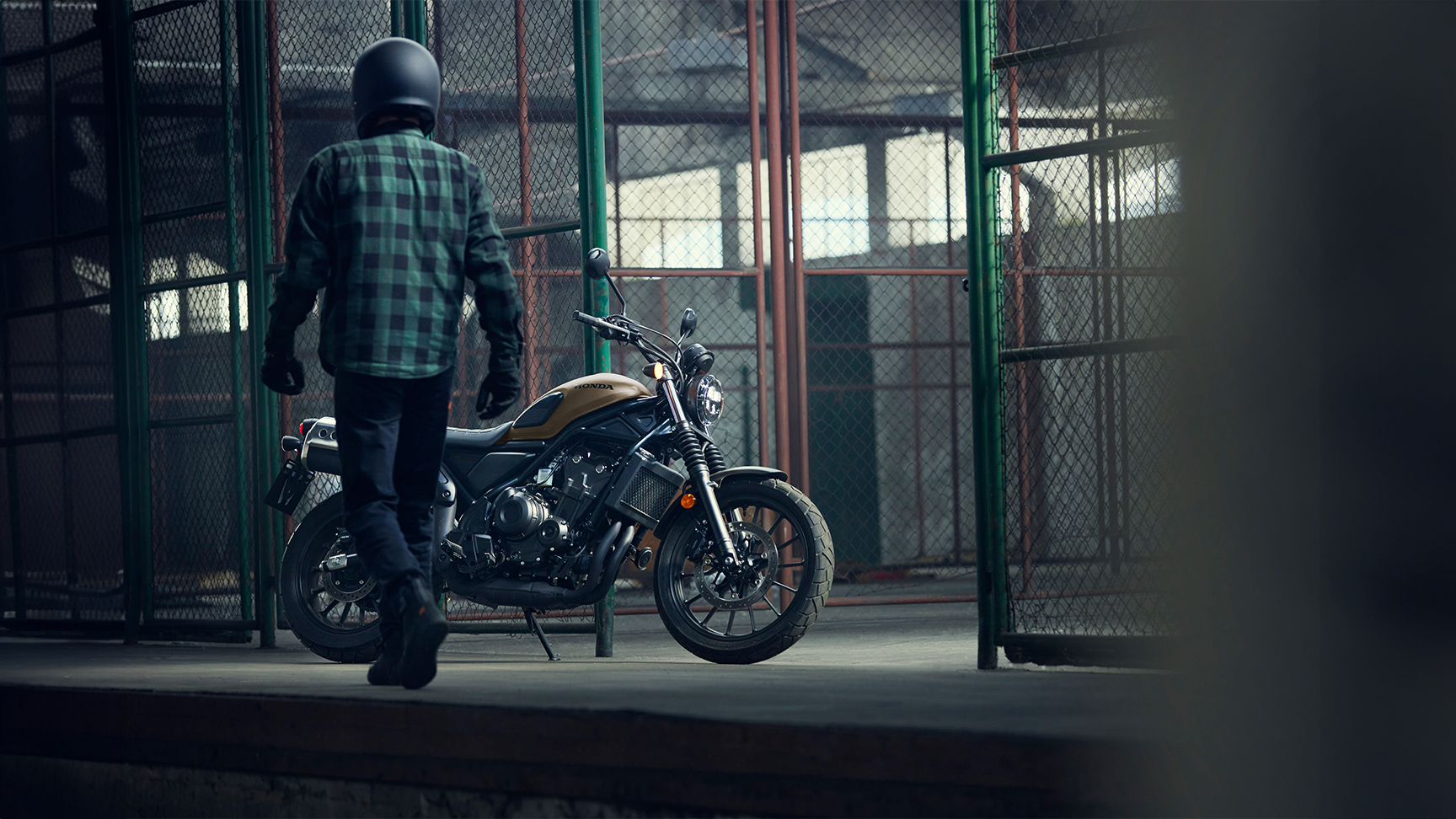 Jazdec kráčajúci vedľa zaparkovaného motocykla Honda CL500 v sklade.