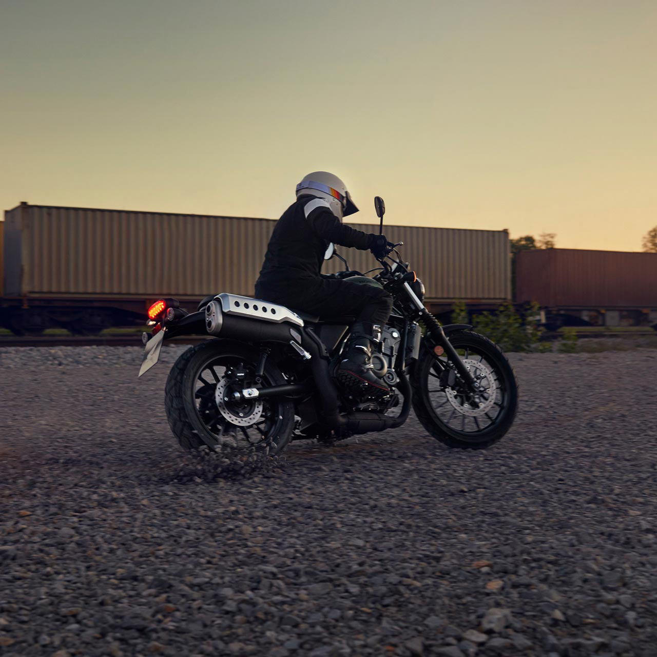 Figurant jazdí na motocykli Honda CL500 v sklade.