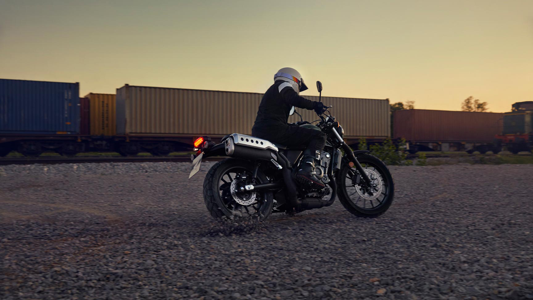 Figurant jazdí na motocykli Honda CL500 v sklade.