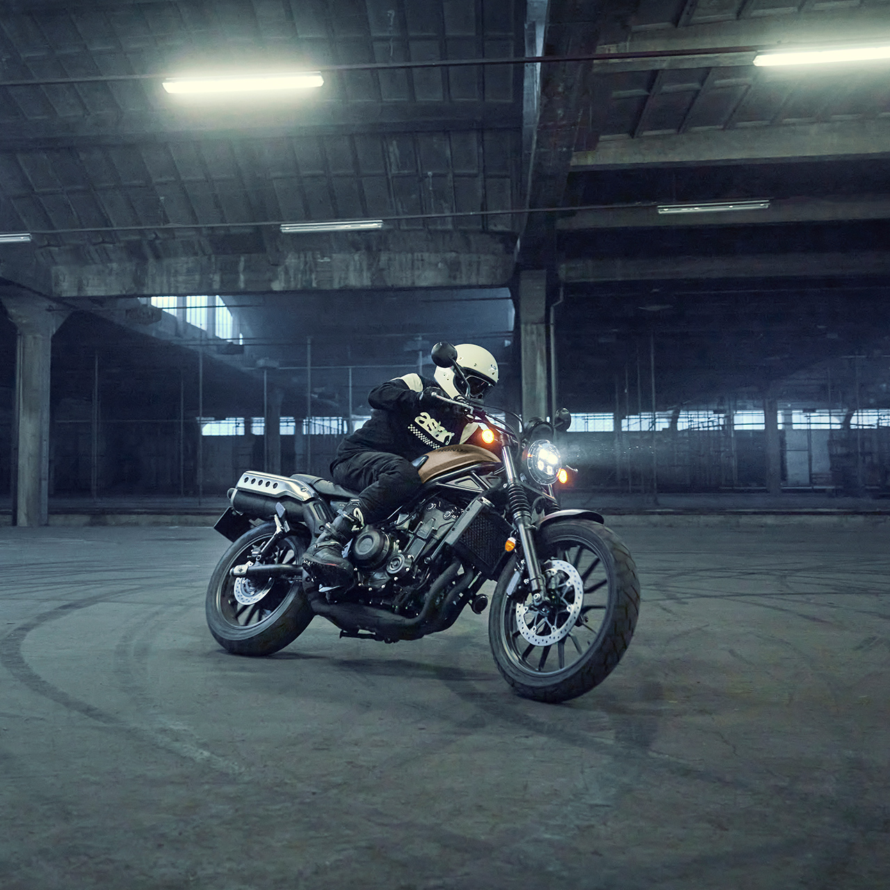 Figurant jazdí na motocykli Honda CL500 na parkovisku.